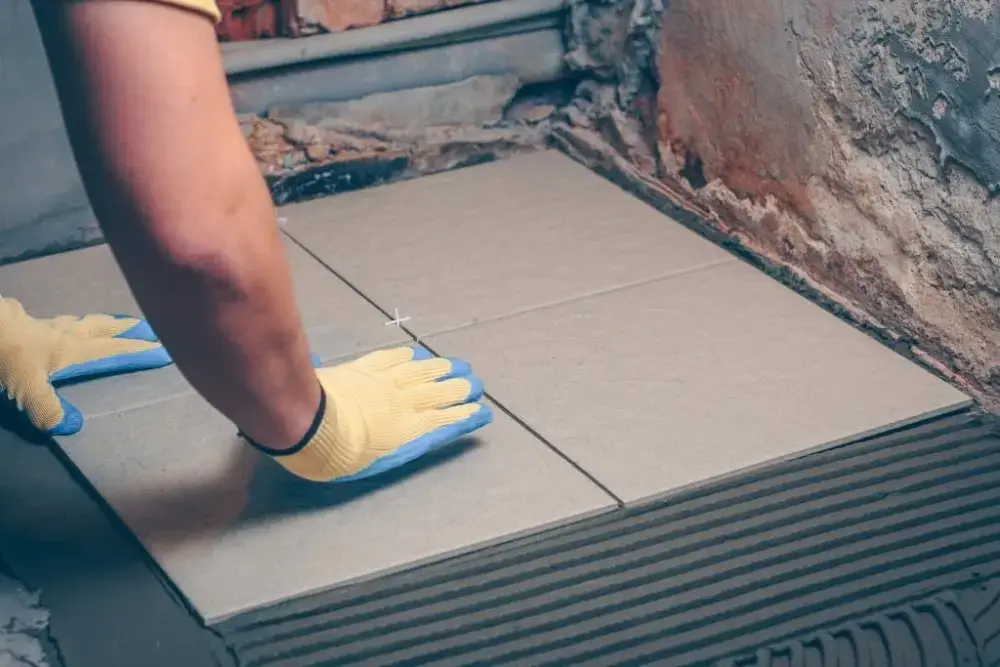 Professional porcelain tile installation showing thinset application and specialized cutting tools